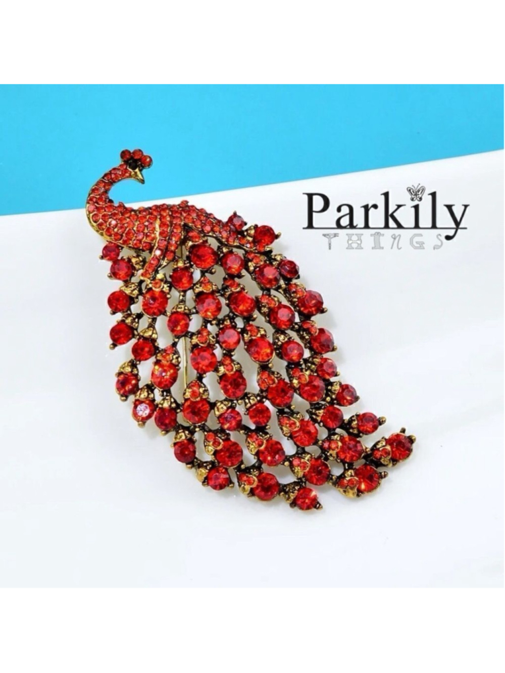 Brooch peacock in sparkly red crystals in a gold and black pin setting